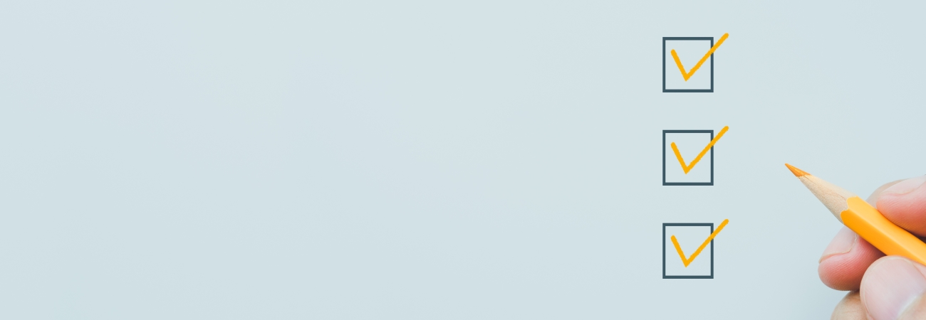 Hand holding a pencil next to list of checkboxes