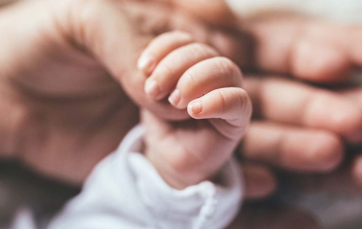 Adult hand holding baby hand