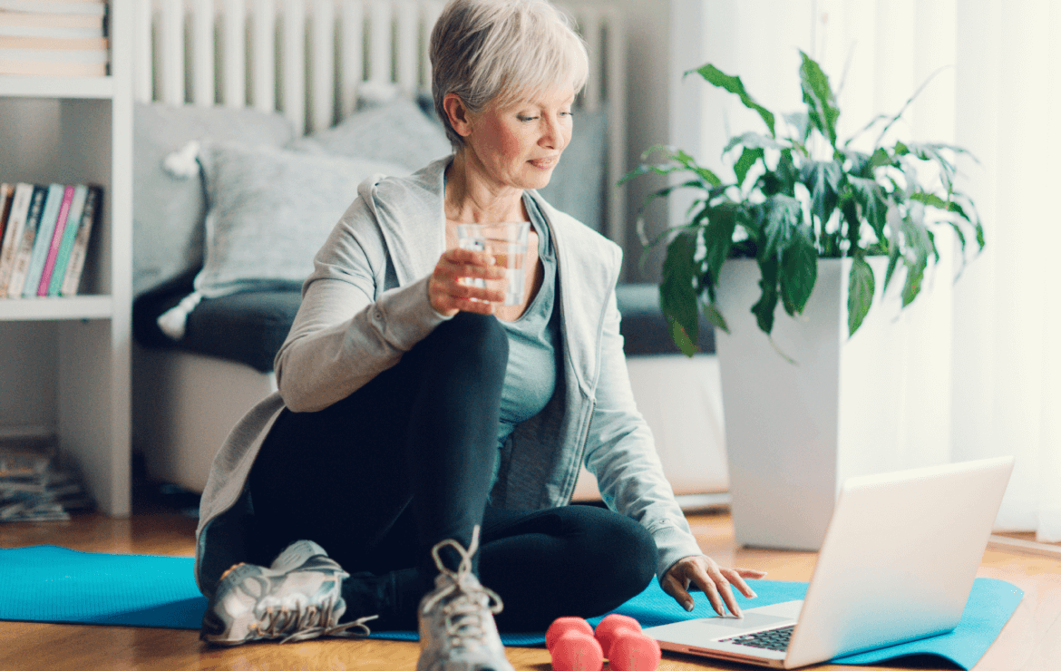 Older woman scrolling on laptop after exercising