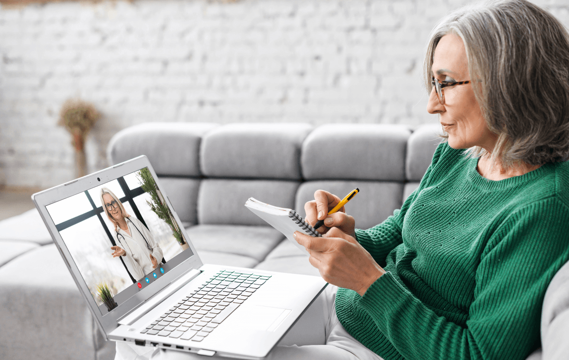 Older woman taking notes during telehealth call