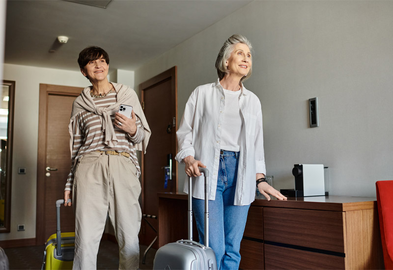 Two older woman with suitcases checking into hotel room