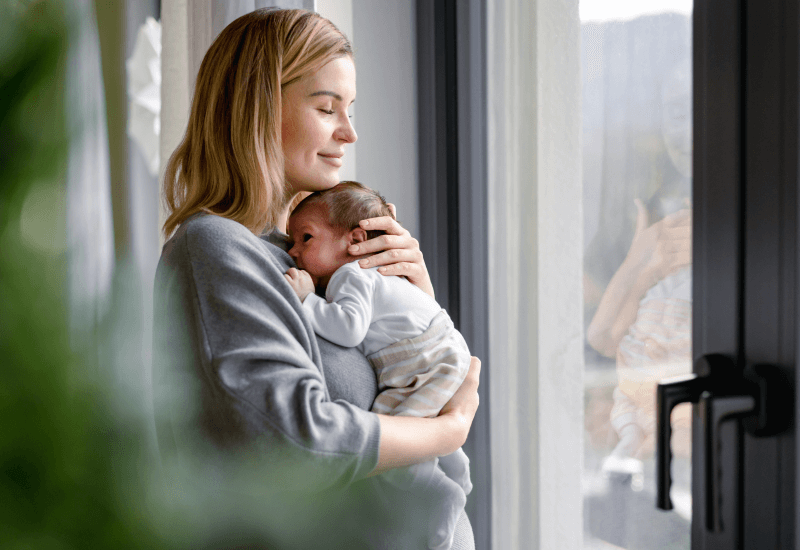 Woman holding newborn baby at home