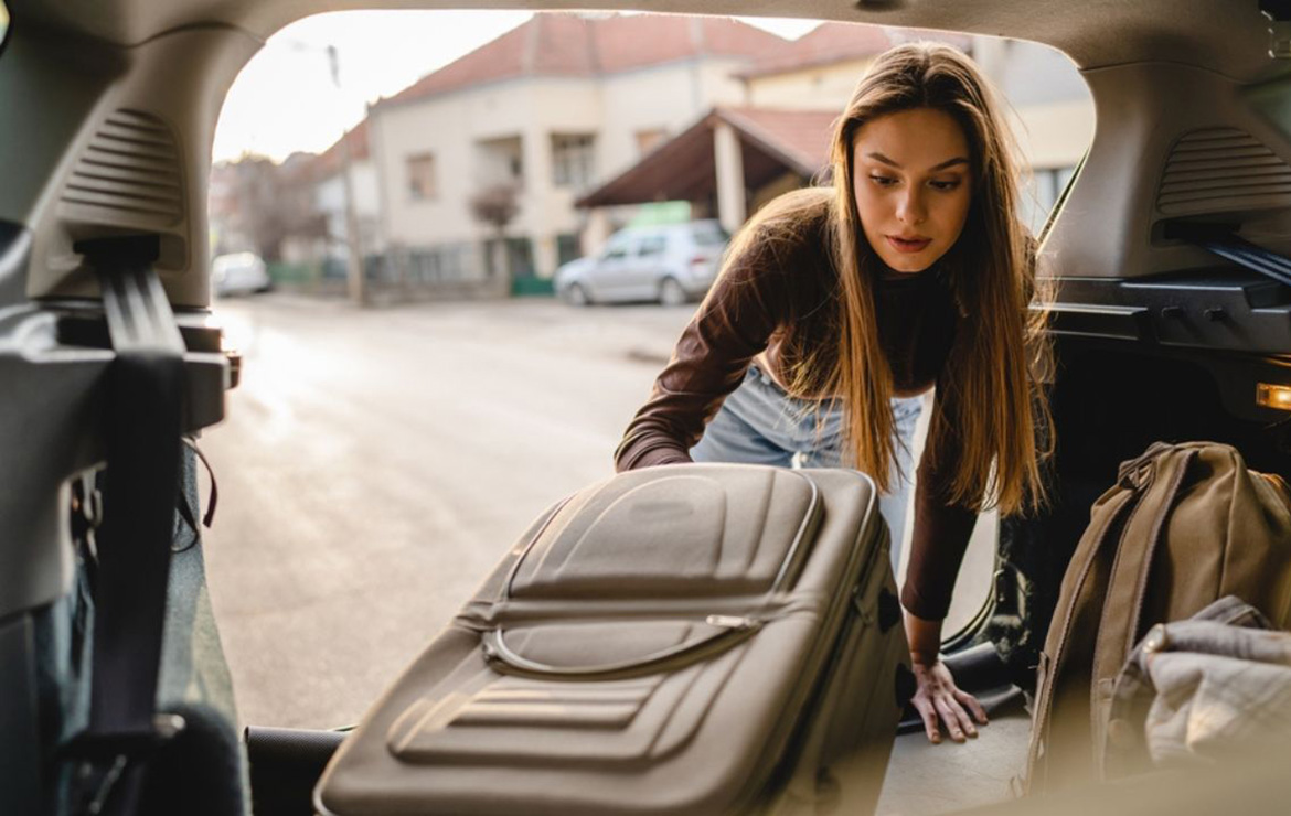 Woman placing luggage inside car