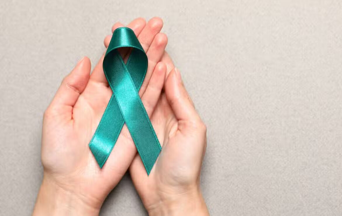 Hand holding teal ribbon for cervical cancer awareness month